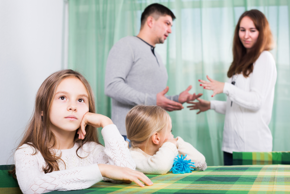 sad man with wife and two unhappy children after quarrel in home