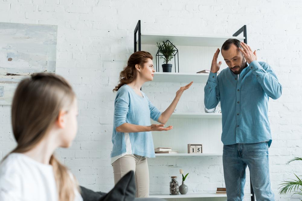 selective focus of offended woman quarreling with husband near kid at home 